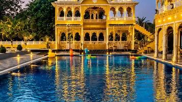 Une vaste et somptueuse piscine dont l’eau reflète un bâtiment orné de coupoles et d’arcades.
