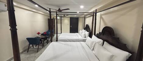 A four-poster bed room with two beds, a desk, and chairs.