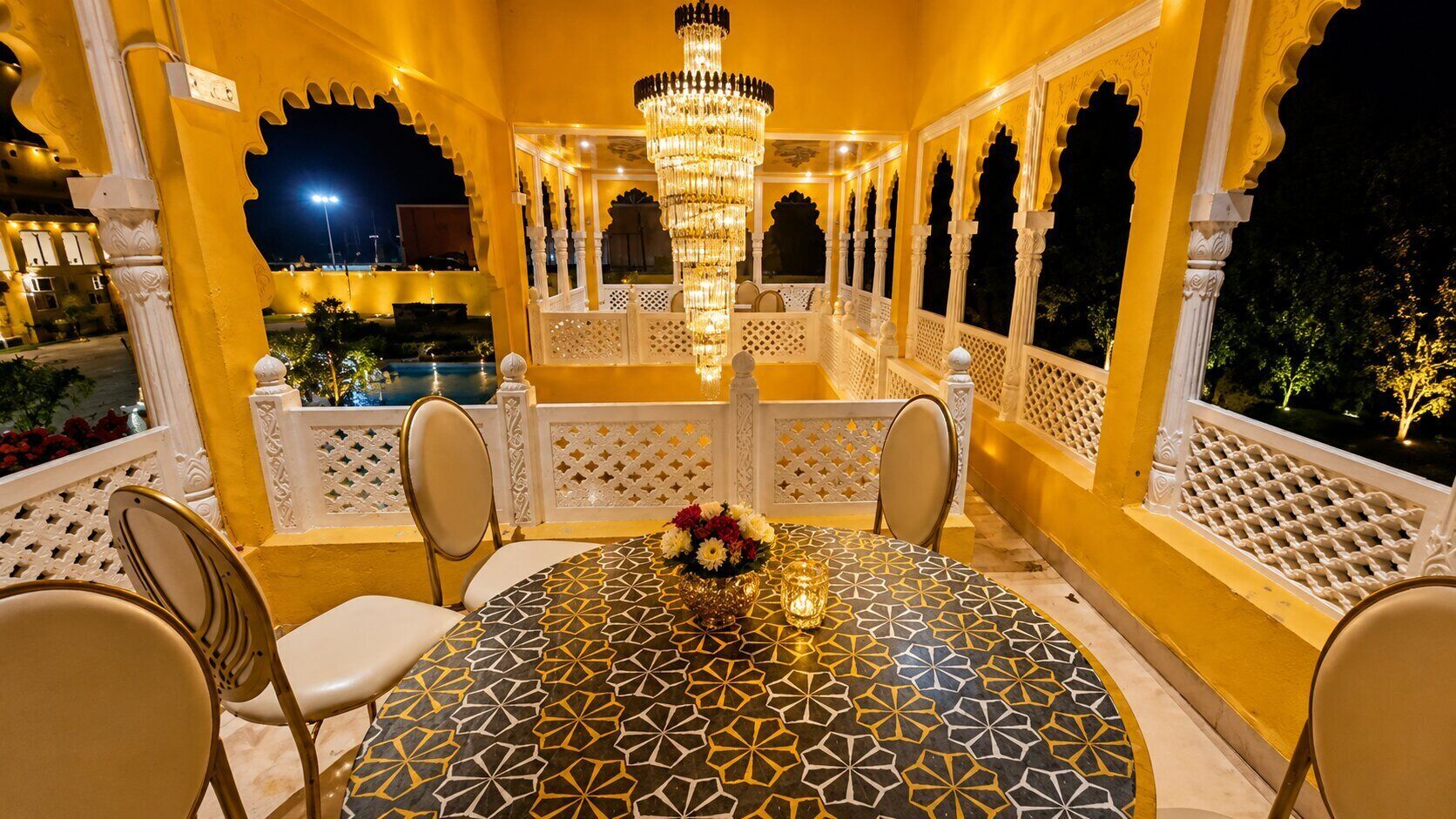 A dining area with a patterned table, chairs, and a chandelier.