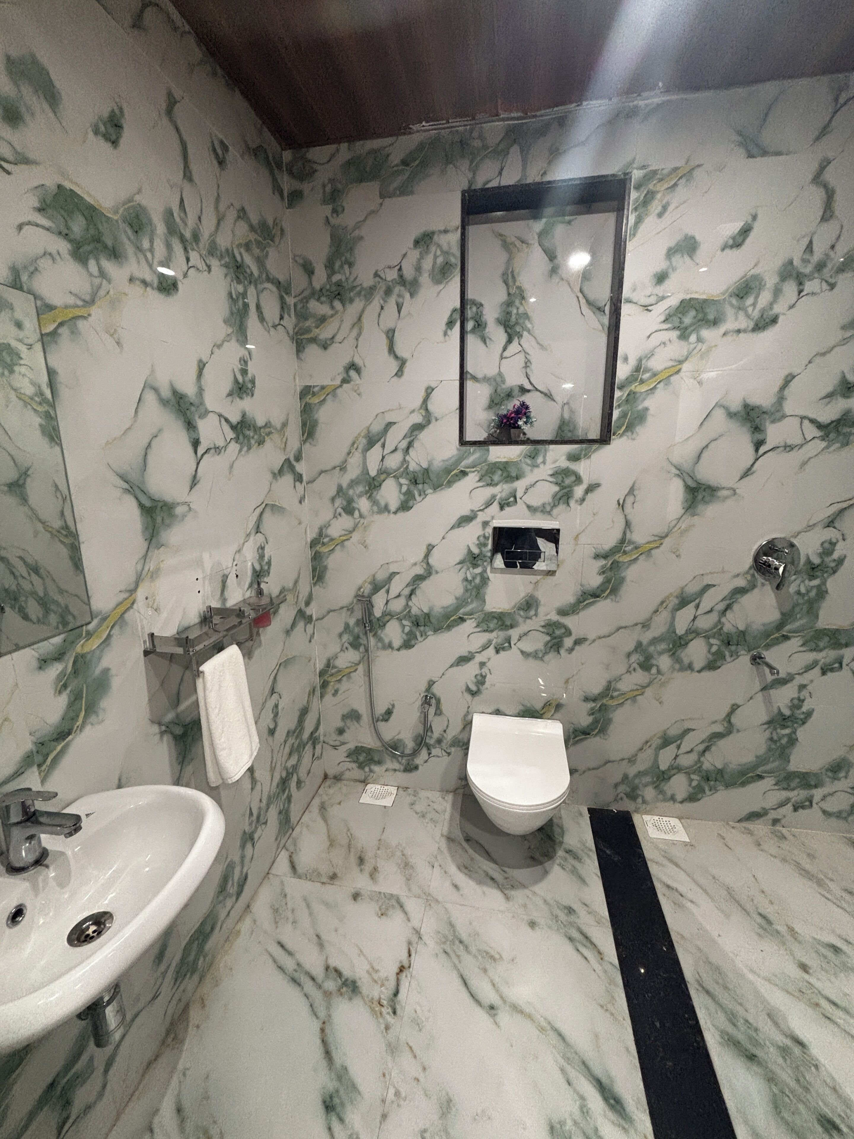 A bathroom with a marble floor, a sink, a toilet, and a shower.