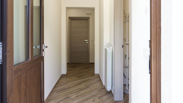 A hallway with wooden flooring, white walls, and a radiator. - Sonia Holiday Home - Jessica Apartment combines intimacy comfort and coziness (Pont-Saint-Martin)