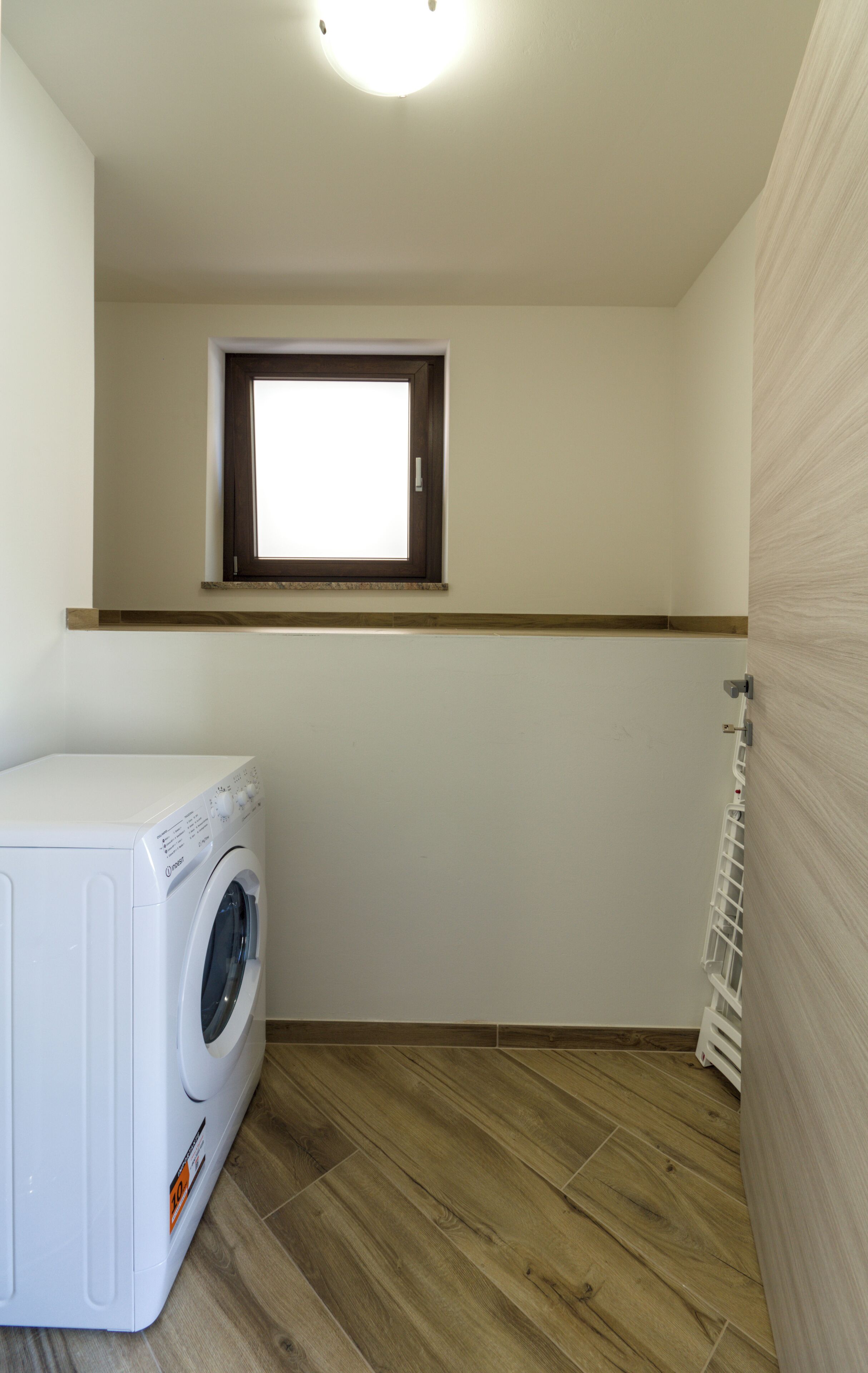 Una lavanderia con lavatrice, una finestra e un termosifone.