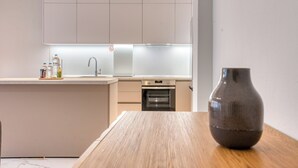 A modern kitchen with a built-in oven, a sink, and a countertop with water bottles. - Thessaloniki Riviera Modern Stay by ΜΡS (Kalamaria)