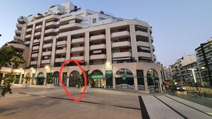 Een hotel met meerdere verdiepingen, balkons, een centrale binnenplaats en potplanten.
