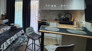 Een compacte hotelkamer met een kitchenette, een eethoek en een bed.