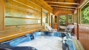 Een houten hut met een jacuzzi en twee rieten stoelen.