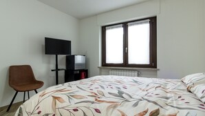 Ein Schlafzimmer mit einem Bett, einem Sessel, einem Fernseher und einem Fenster.