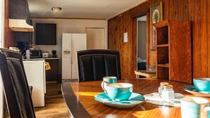 Un comedor con una mesa de madera, sillas y una cocina al fondo.