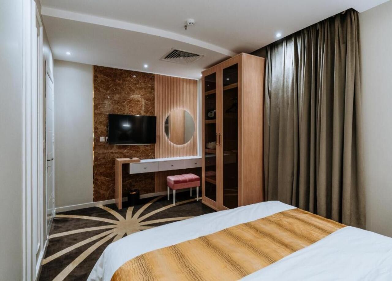 Una camera d'albergo con un letto, una scrivania con televisore, uno specchio e un armadio.