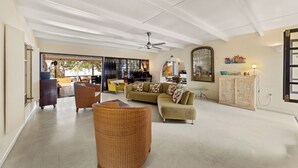 Uma sala ampla com sofá, cadeira de vime e um armário.