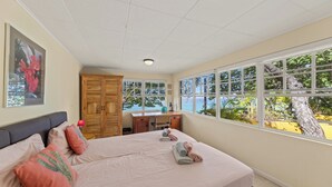 Quarto com cama grande, escrivaninha e vista para o exterior.