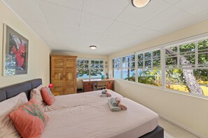 Ein Schlafzimmer mit einem großen Bett, einem Schreibtisch und Blick ins Freie.