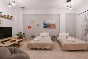 Ein modernes Hotelzimmer mit zwei Betten, einem Fernseher, einem Schreibtisch und einem Bild an der Wand.