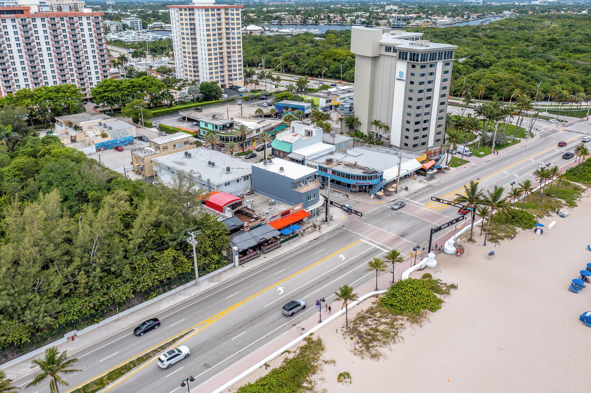 An aerial view of a coastal urban area with high-rise buildings, a main road, and a beach.