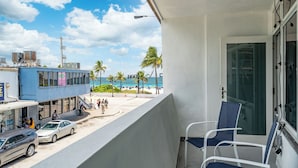 A balcony with a view of a beach and a building with air conditioning units. - BeachSide 9th Residences (Fort Lauderdale)