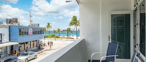 Un balcón con vistas a la playa y un edificio con unidades de aire acondicionado.