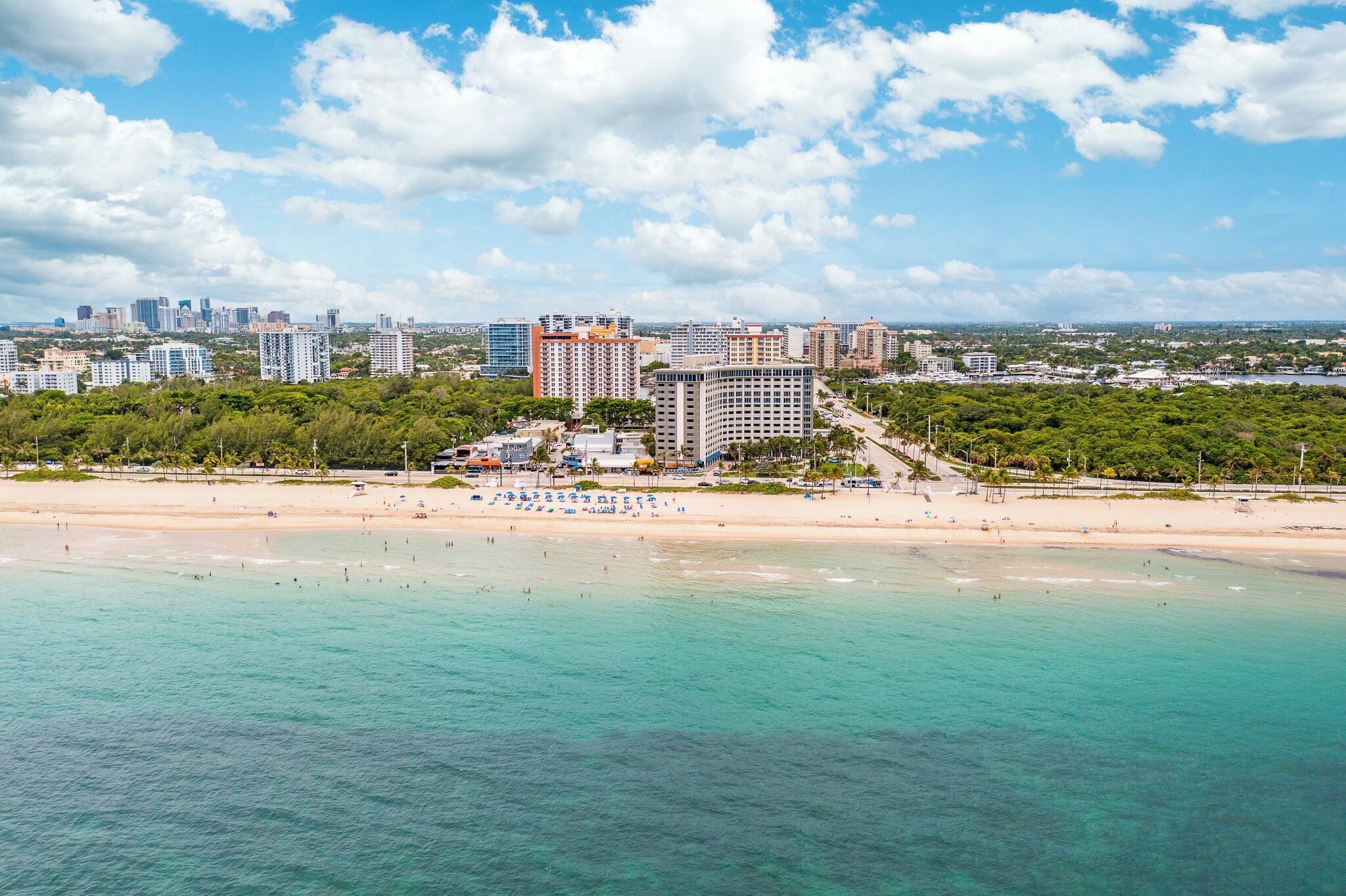 A coastal cityscape with a beach, high-rise buildings, and a clear sky.