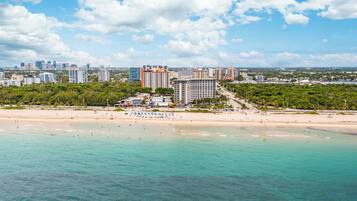 A coastal cityscape with a beach, high-rise buildings, and a clear sky.