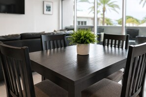 A dining area with a dark wooden table, four chairs, and a potted plant. - BeachSide 9th Residences (Fort Lauderdale)