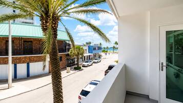 Een balkon met uitzicht op een straat, palmbomen en gebouwen.