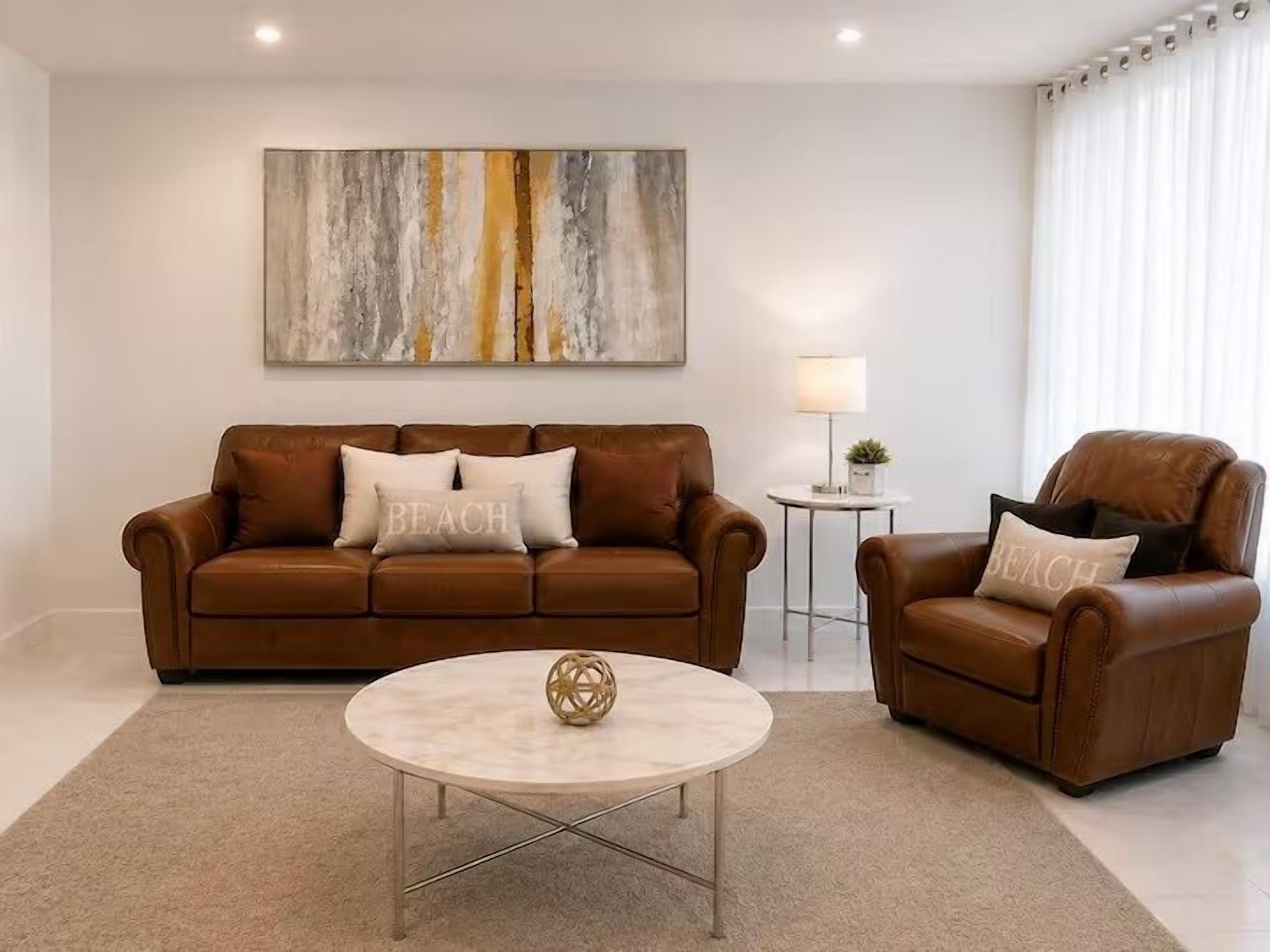 Ein Wohnzimmer mit einem braunen Ledersofa, einem runden Couchtisch und einem Beistelltisch mit Lampe.