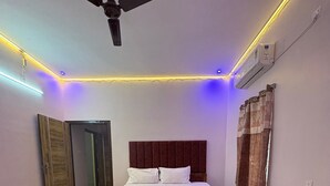 A bedroom with a bed, a ceiling fan, and LED strip lighting along the ceiling. - Sam Premium  (Bhubaneshwar)