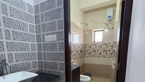 A bathroom with a white sink, a toilet, and a shower area. - Sam Premium  (Bhubaneshwar)