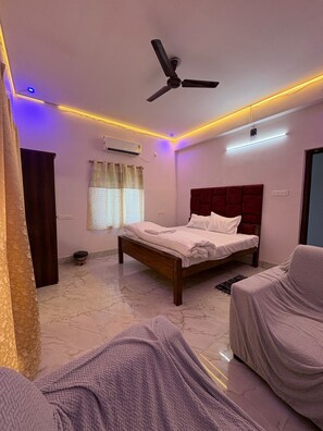 A bedroom with a bed, a ceiling fan, an air conditioning unit, and a window with curtains. - Sam Premium  (Bhubaneshwar)