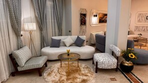 Een moderne woonkamer met een bank, fauteuil, salontafel en decoratieve elementen.