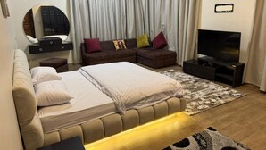 Un dormitorio con una cama grande, un sofá, un televisor y un espejo.