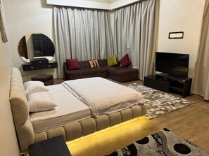 Ein Schlafzimmer mit einem großen Bett, einer Couch, einem Fernseher und einem Spiegel.