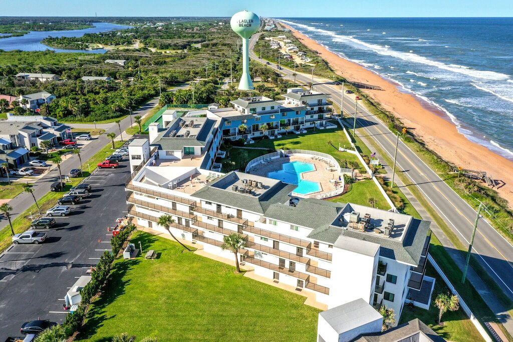A resort with multiple buildings, a swimming pool, and a beach view.