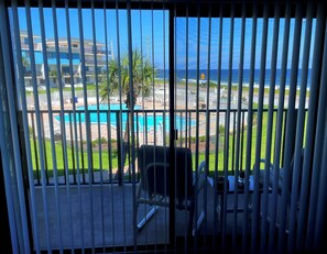 Uma varanda com vista para uma piscina, uma cadeira e uma mesa.