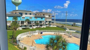 Vista de un hotel con piscina, playa y una torre de salvavidas.