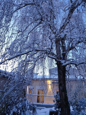 A snow-covered tree in front of a building with a warm light visible through the windows. - 🔥 Favourite : "Chalet Cosy Neuf ❤️ 8 pers - Historical heart of Fontenay" (Fontenay-le-Comte)