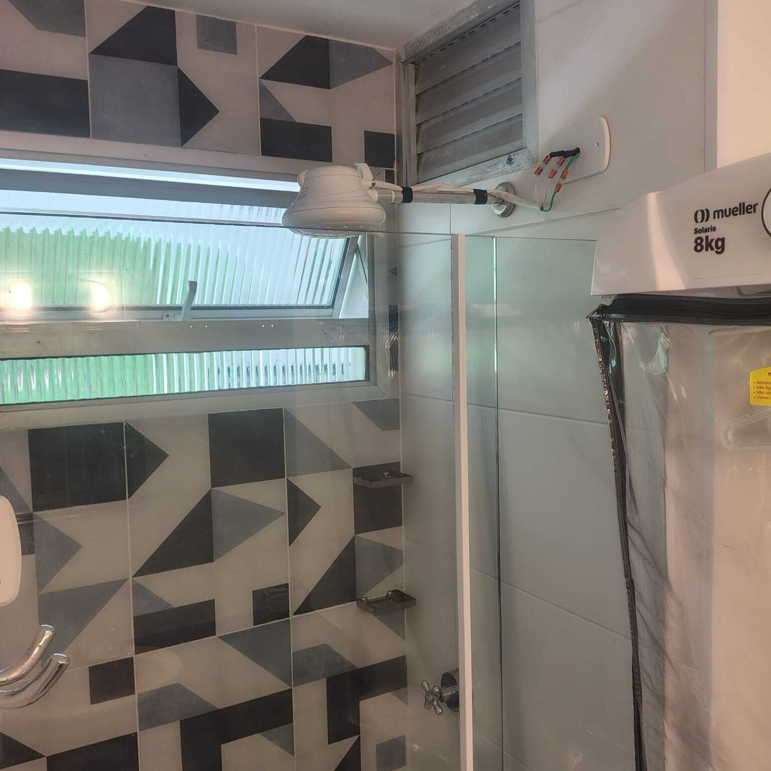 A bathroom with geometric patterned tiles, a glass shower enclosure, a skylight, and a solar water heater.