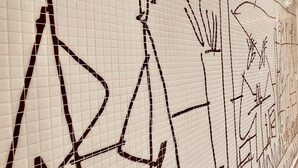 Een betegelde muur met abstracte zwart-lijnl tekeningen.