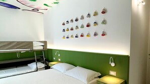 Een kamer met stapelbedden, een nachtkastje met lamp en een wand met meerdere hangende lampen.