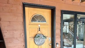 A wooden door with a 'hello' sign, a black-framed window, and a black doormat. - Hillside Haven Anchorage (Anchorage)