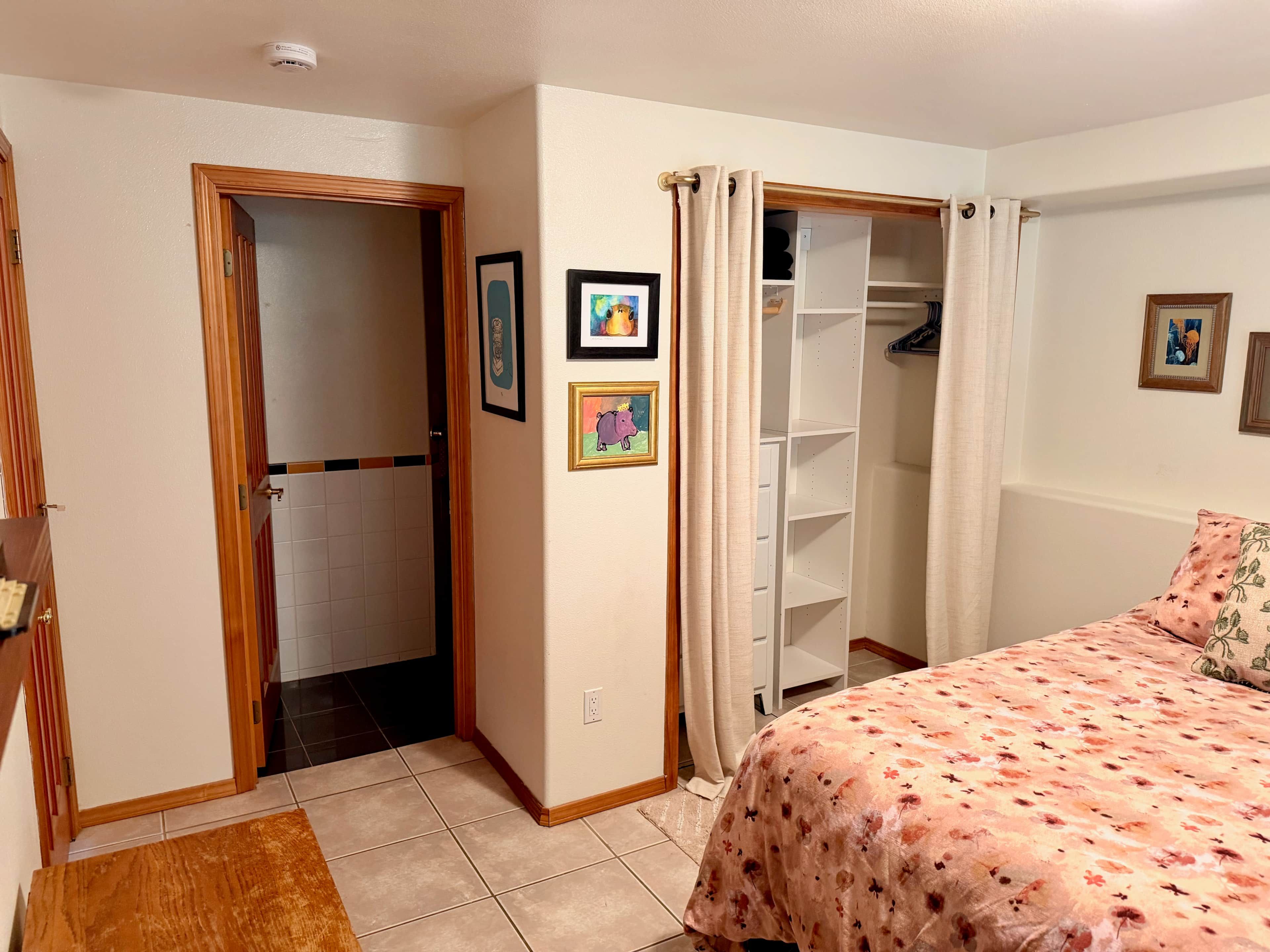 Une chambre à coucher avec un lit, une armoire, une porte donnant sur une autre pièce et un petit tapis.