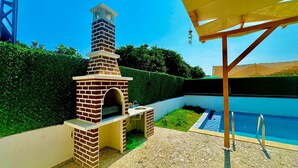 A brick outdoor kitchen with a chimney, a pool, and a pergola. - History at Your Doorstep: 3-BR Pool Villa in Demre - Near St. Nicholas Church (Antalya)
