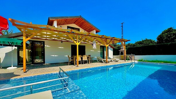 A modern house with a swimming pool, wooden pergola, and outdoor seating area. - History at Your Doorstep: 3-BR Pool Villa in Demre - Near St. Nicholas Church (Antalya)