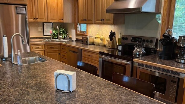 Una cocina moderna con encimeras de granito, electrodomésticos de acero inoxidable, armarios de madera y una isla central.
