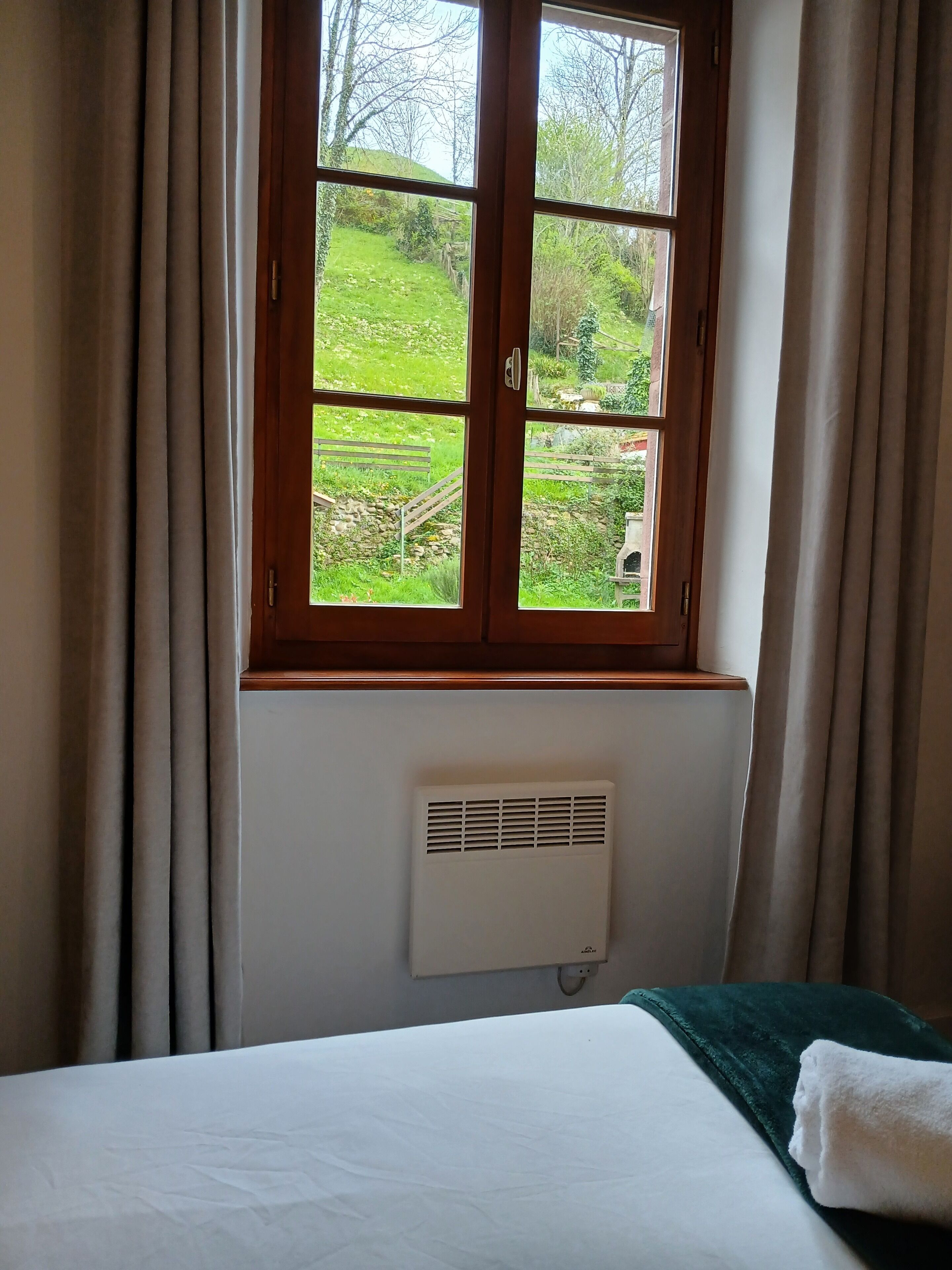 Une pièce avec un lit, une fenêtre avec des rideaux et un climatiseur fixé au mur.