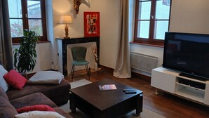 A living room with a sofa, a coffee table, a TV on a stand, a fireplace, a plant, and a large bull skull decoration.