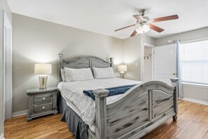 A bedroom with a wooden bed, nightstands, a ceiling fan, and a window with blinds. - White Shores, Pet Friendly, Beautiful massive Pool, Short walk to the Beach. (Miramar Beach)