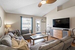 A living room with a sofa set, a coffee table, a TV, and a ceiling fan. - White Shores, Pet Friendly, Beautiful massive Pool, Short walk to the Beach. (Miramar Beach)