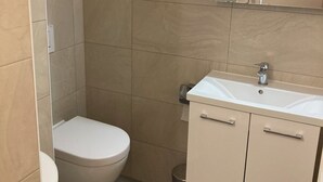 A bathroom with a toilet, sink, and mirror.