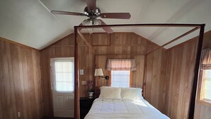 A four-poster bed in a room with wooden walls and a sloped ceiling. - Cozy Cabin on Angelina River near Lake Sam Rayburn-Pool, Boat Parking, Fishing (Jasper)