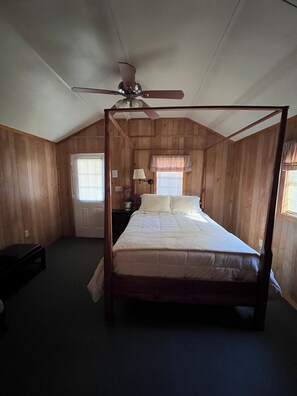 A four-poster bed in a room with wooden walls and a sloped ceiling.